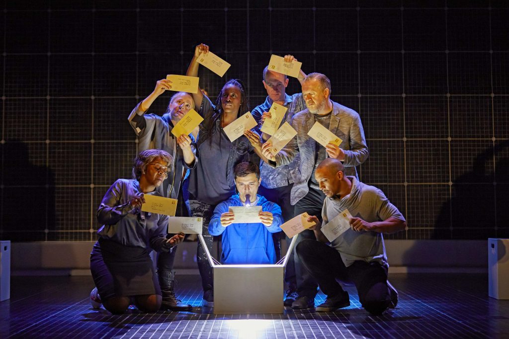 Joshua Jenkins as Christopher Boone holding letters surrounded by the company of The Curious Incident of the Dog In the Nighttime also holding letters.