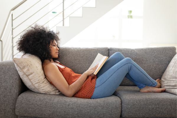 woman reading on a grey couch.