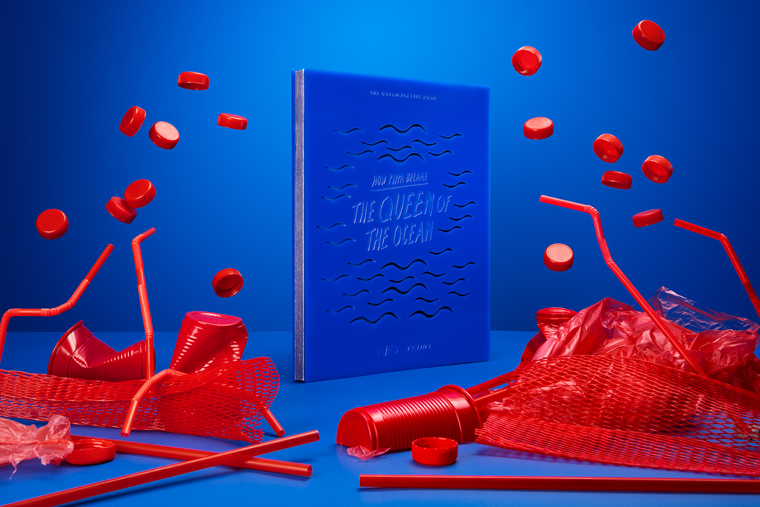 the Queen of the Ocean book with  red plastic waste surrounding it.