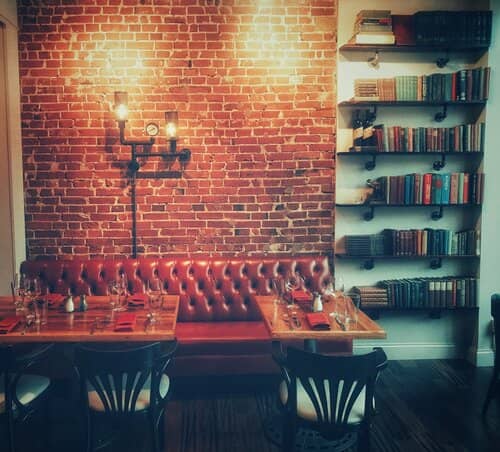 dimly-lit-restraunt-with-red-seats-and-a-bookshelf-on-the-side