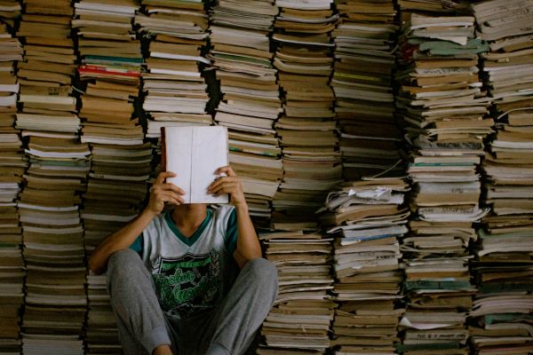 boy reading in front of stacks of books