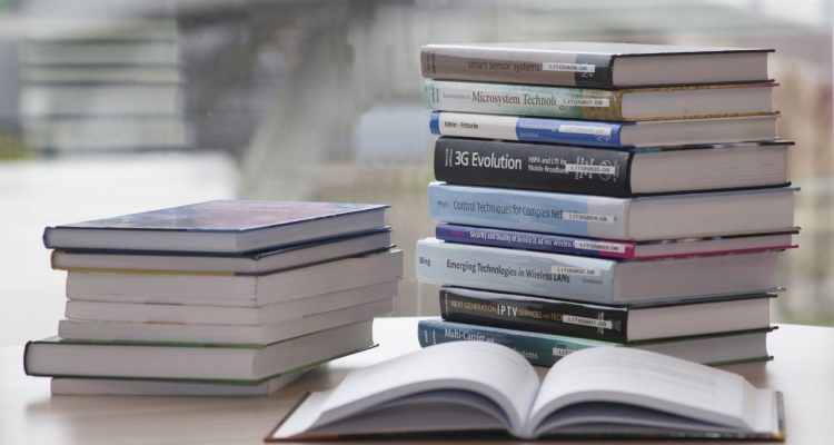 stacked text books on a desk