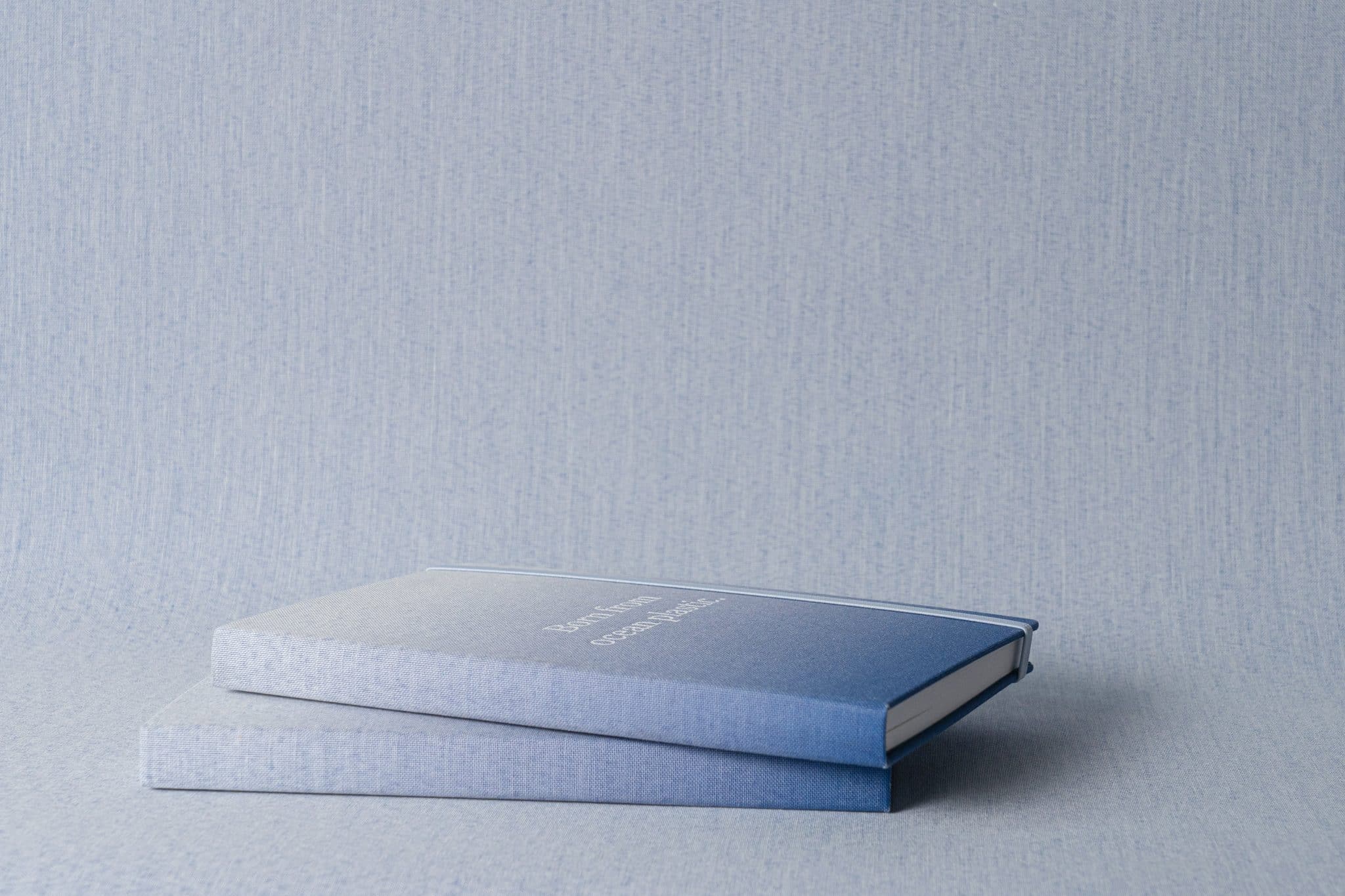Two blue ombre notebooks on a similar tones blue background.