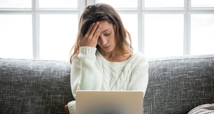 Woman with laptop looking down stressed