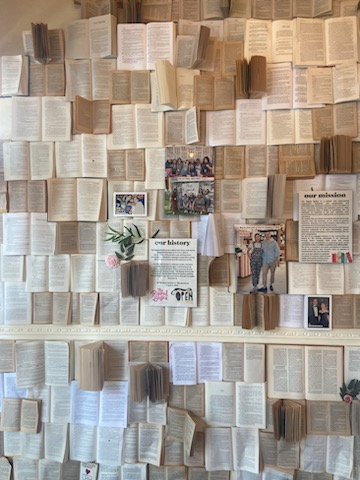 a wall covered in open books along with pictures and flowers