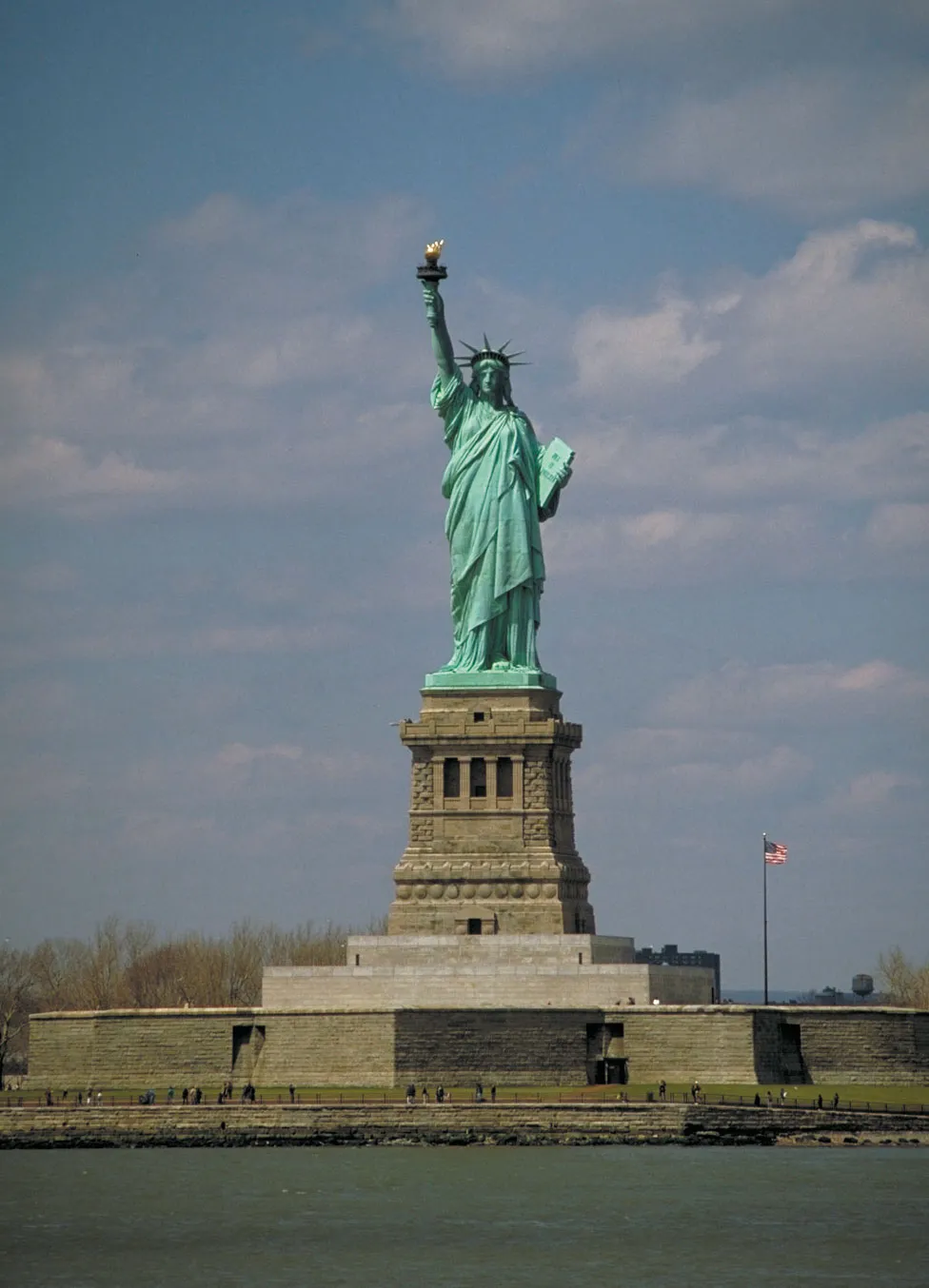 Statue of Liberty with blue sky and American flag in background