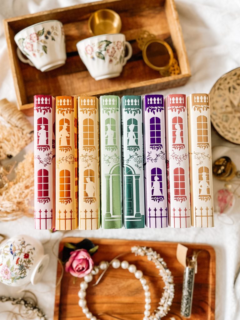 Flatlay of an organized, colorful book series against a white background with decorations placed around it.