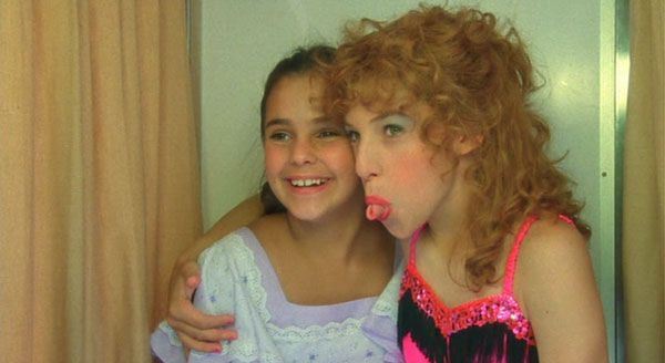 Two girls embracing in a photo booth. 