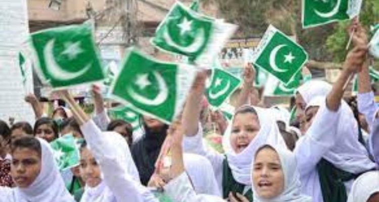 People in a crowd waving miniature Pakistan flags to celebrate Independence Day