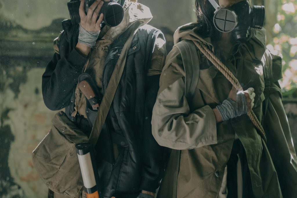 Two people wearing gas masks and survival gear