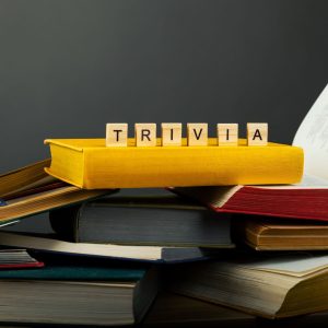 Stacked up books with scrabble letters on top that spell "trivia."