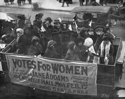 Women traveling in a cart with a sign that reads "Vote For Women"