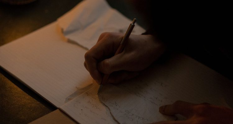 a hand is writing poetry on a piece of paper