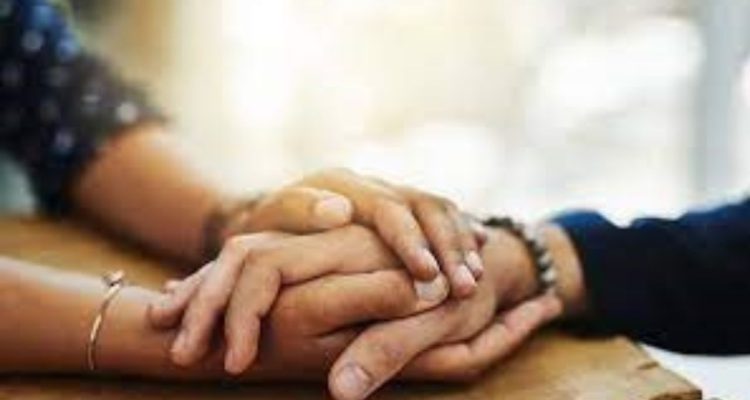 One person wrapped their hands around one of someone else's in a comforting gesture