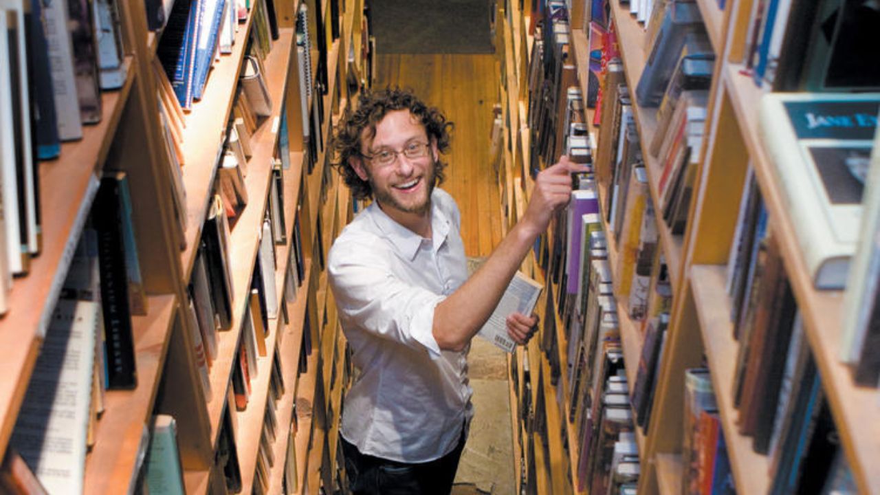 Man standing in between shelves smiling