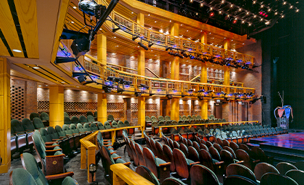 theater filled with empty seats on the ground and up in the balcony as lights covers the stage