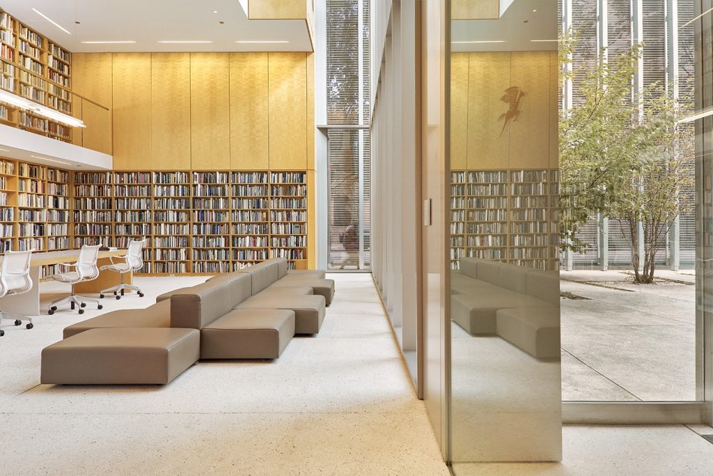 Shelves of books near chairs and couches in glass building