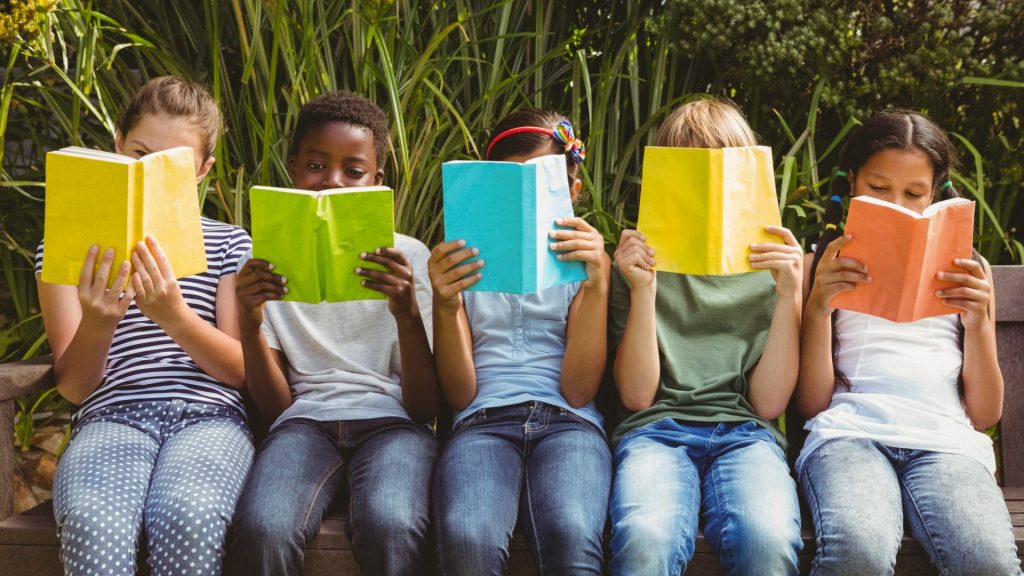 Kids sitting on a bench reading books