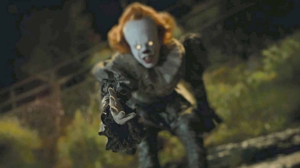 Pennywise with glowing eyes reaching out 