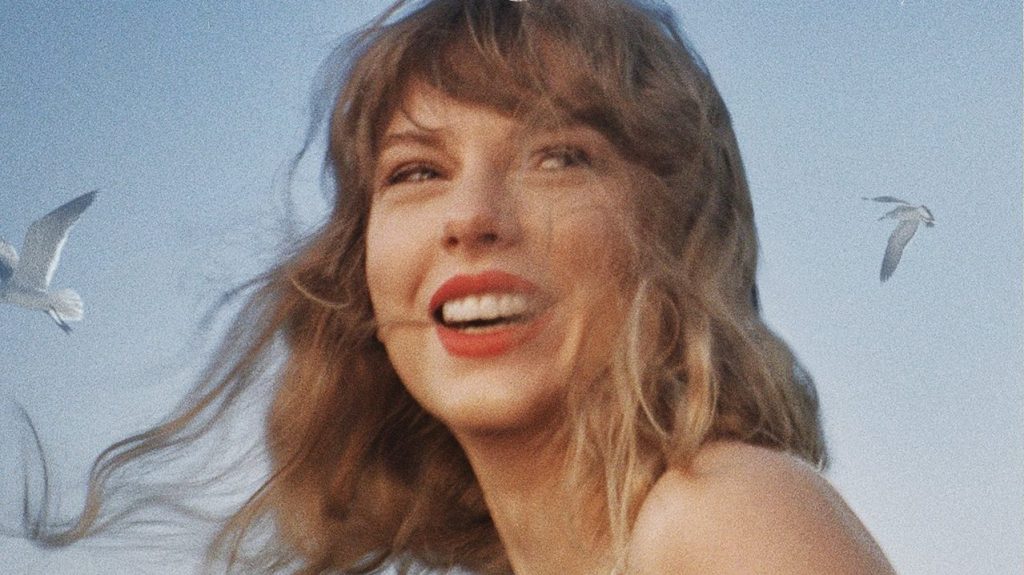 Taylor Swift smiling in front of a blue sky with seagulls in the background