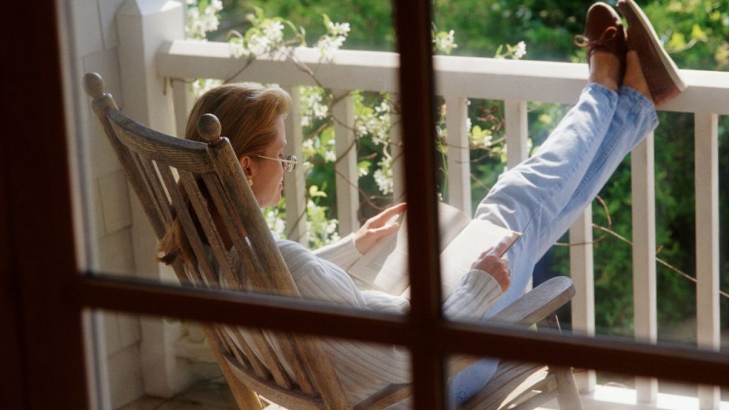 A woman reading comfortably on her porch 