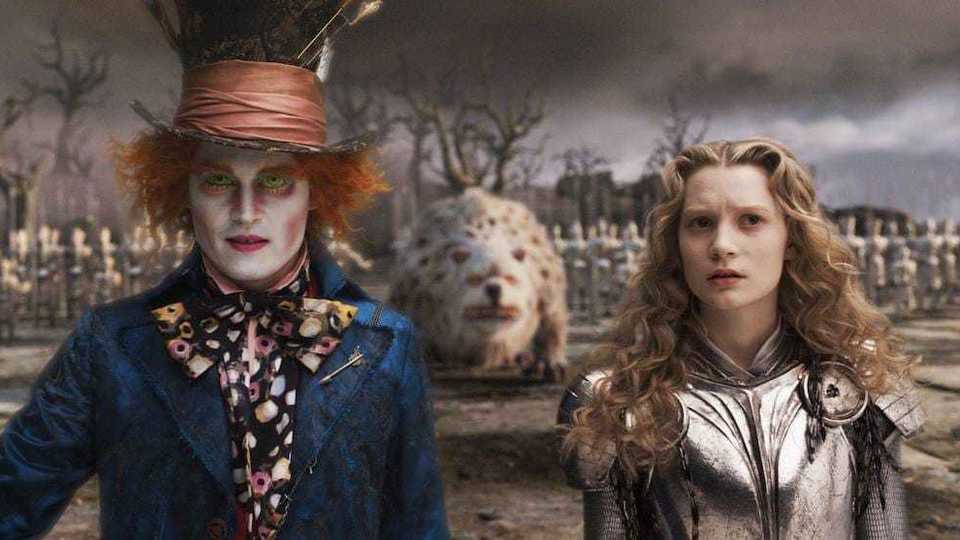 The Mad Hatter in a blue suit next to Alice in a suit of armor from Disney's Alice in Wonderland with Tim Burton.
