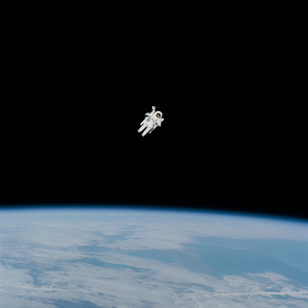 Astronaut in a white space suit floating above the Earth.