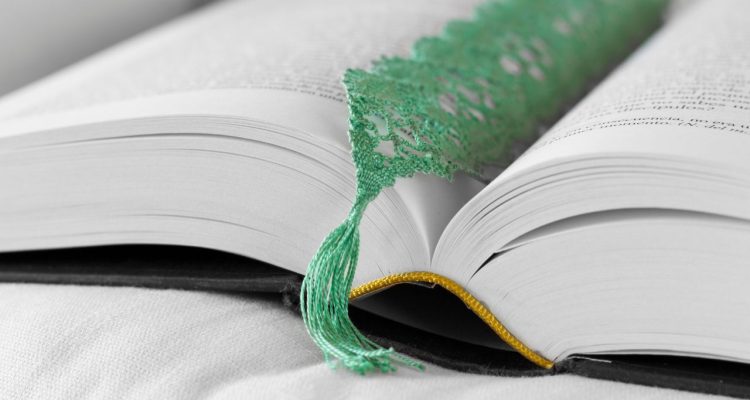 A book opened to a page with a green lace bookmark inside.
