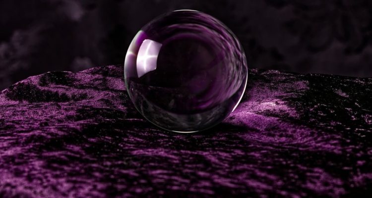 A clear crystal ball on top of a purple velvet cloth