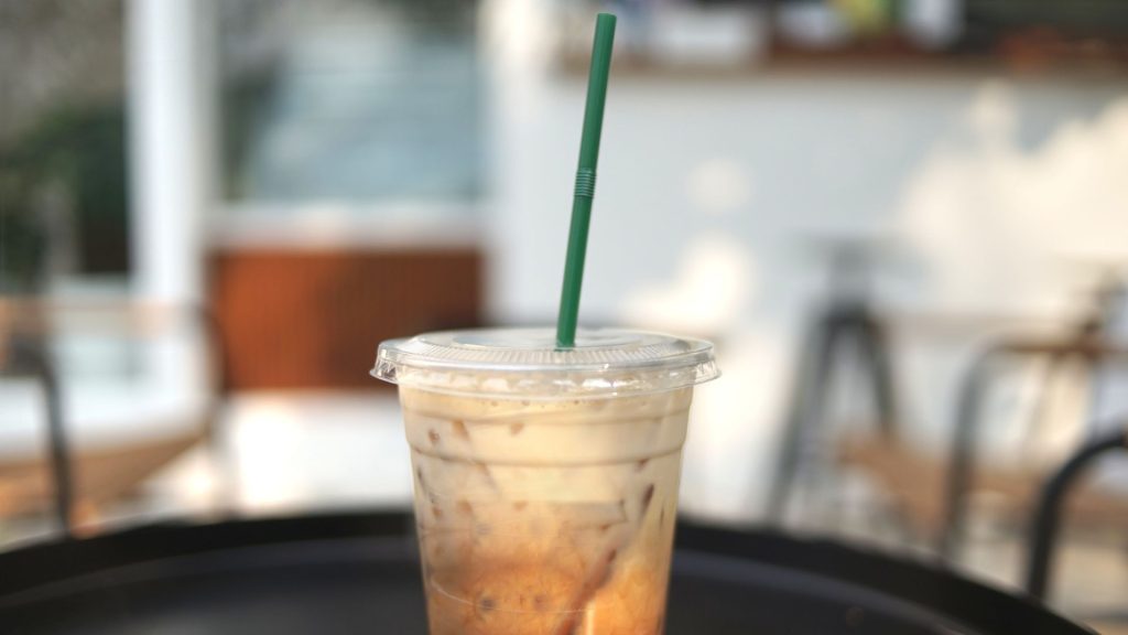 Delicious looking iced coffee with a cozy coffee shop in the background