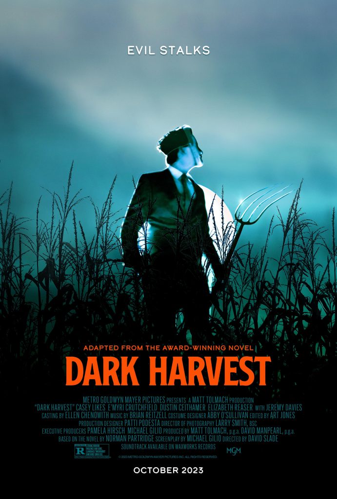 Movie poster for Dark Harvest featuring a man in a mask holding a winnowing fork in a cornfield in front of a dark blue sky.