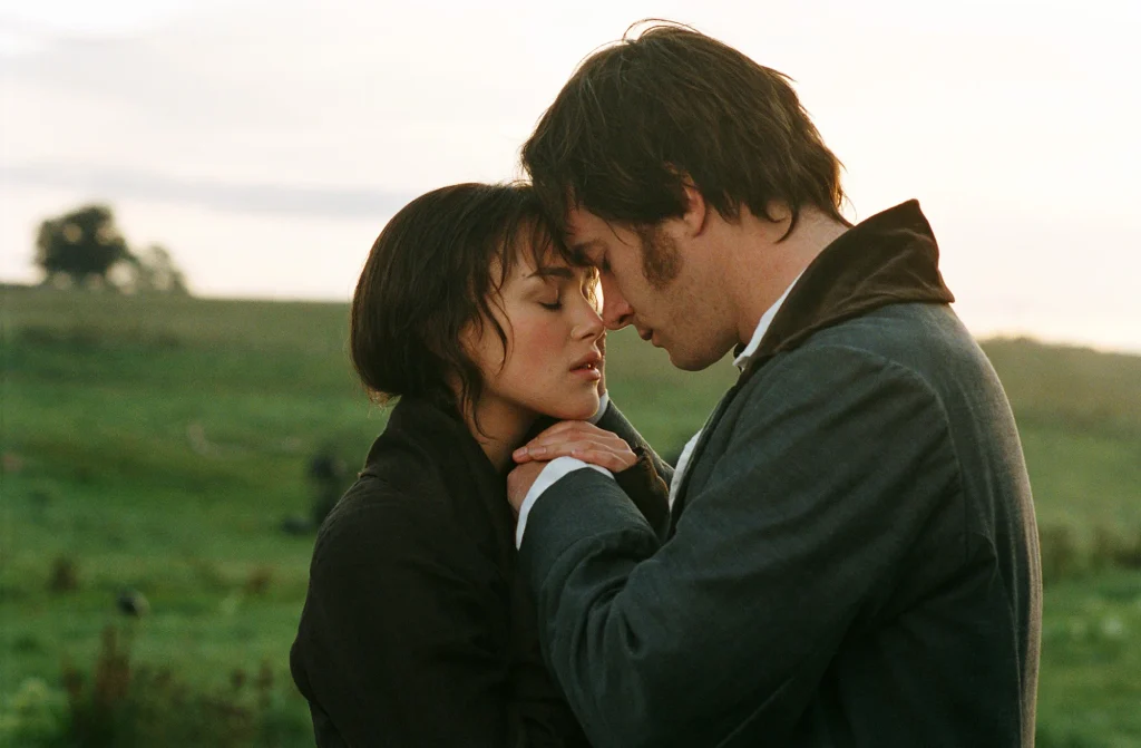 Elizabeth and Darcy dressed in brown and dull clothes as they embrace on the moor landscape. 