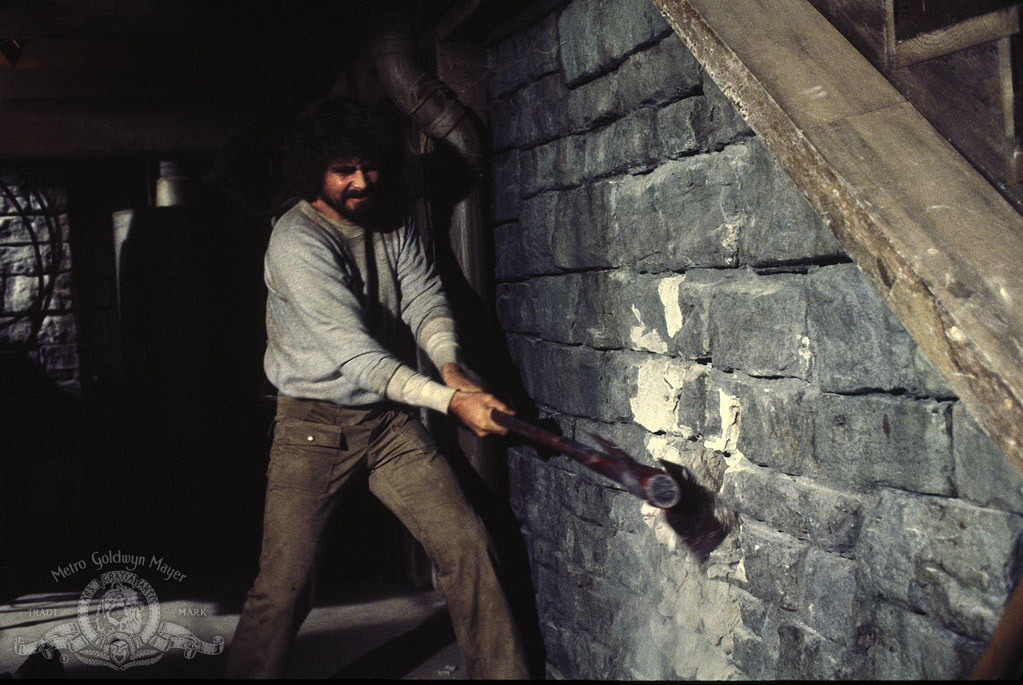 George Lutz breaking a brick wall in the Amityville house basement with a sledgehammer. 