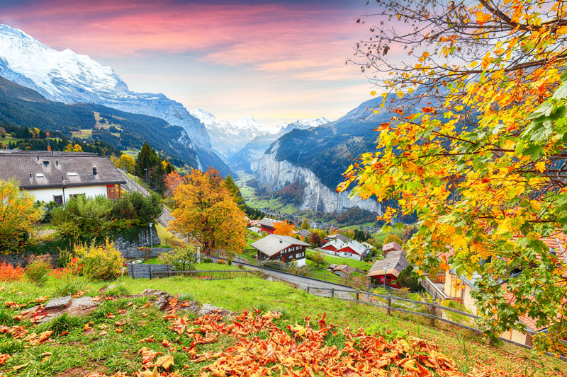 The hills and valley of Interlaken during the Fall with occasional red houses.