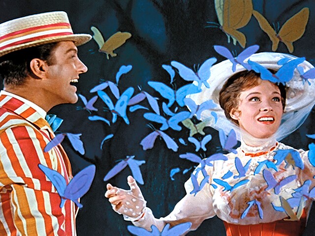 Image shows Julie Andrews as Mary Poppins surrounded by animated blue butterflies with Dick van Dyke standing next to her.
