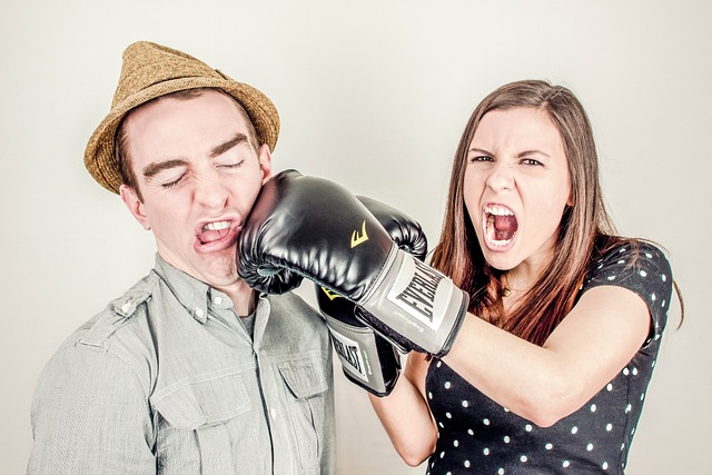 A girl with boxing gloves hitting a man next to her. 