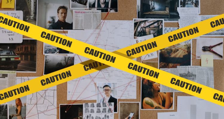 Yellow caution tape covering a cork board with notes and pictures connected by red string.