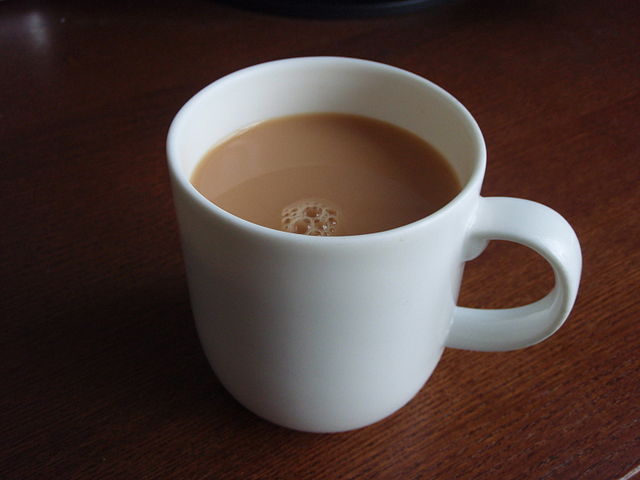 White mug of tea with cream. 