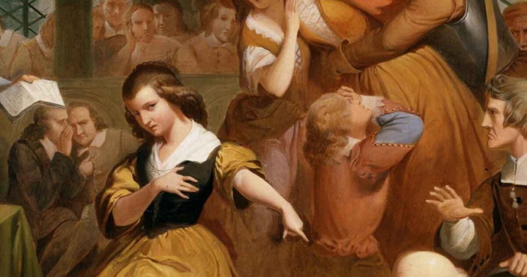 Painting of Salem witch trials; young girl in a dress points at something unseen while men whisper in the background and a young girl hugs an older woman
