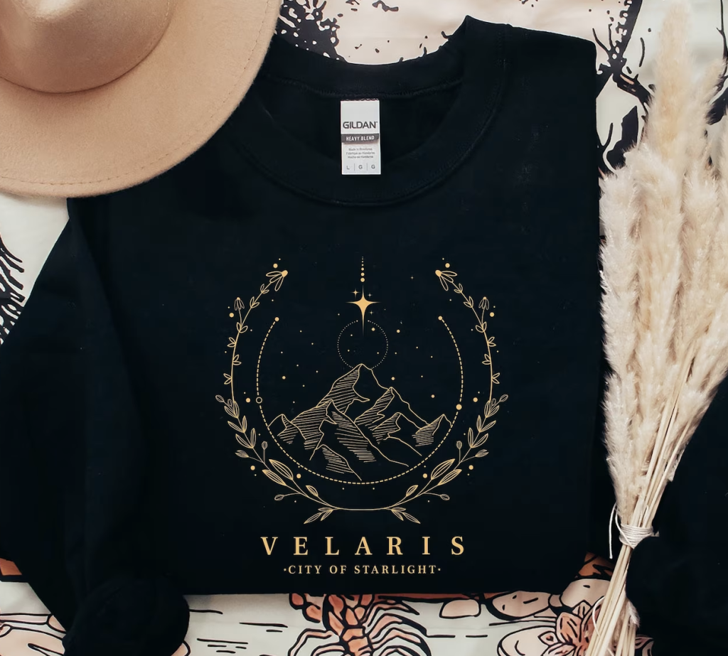 A black sweatshirt with a Velaris scene in gold; created by iPrintasty Co on Etsy