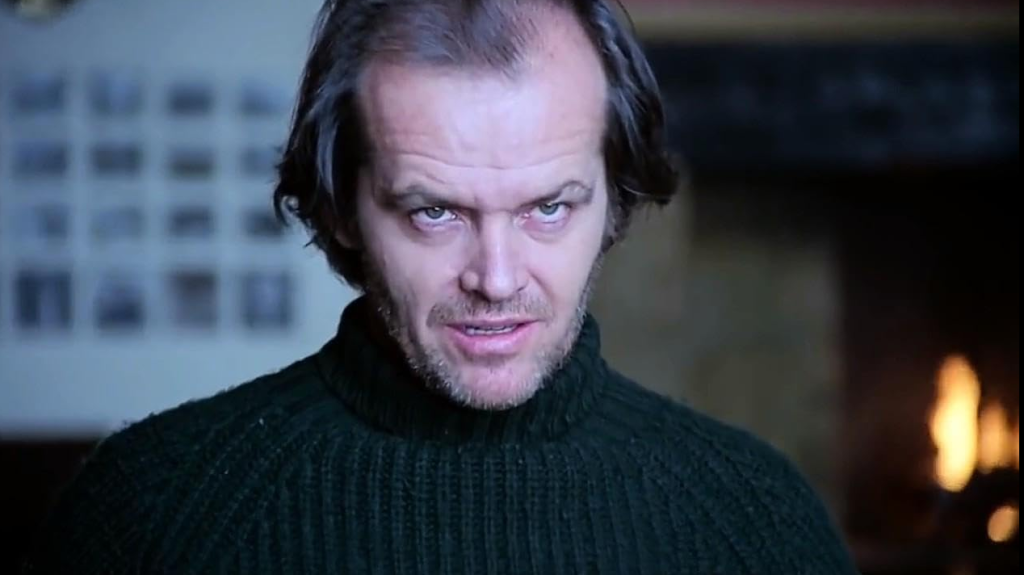 Jack Torrance looking toward the camera with his head tilted down. The background is blurred, allowing the eyes to focus on the character's creepy and mysterious expression.