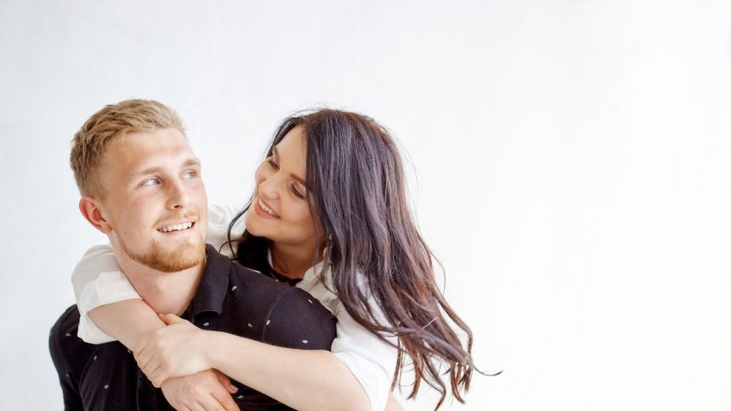 woman behind a man with her arms around his neck
