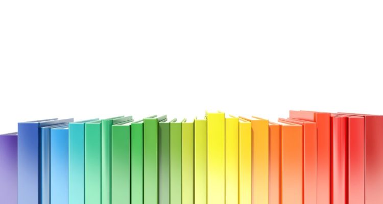 A line of books organized by rainbow color, starting with red.