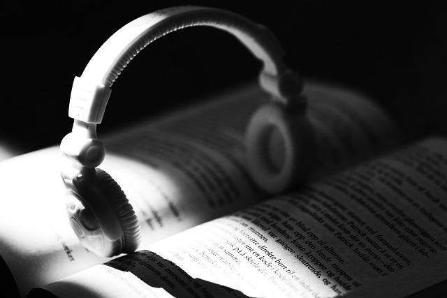 A black and white book with headphones sitting in the spine of the open pages.