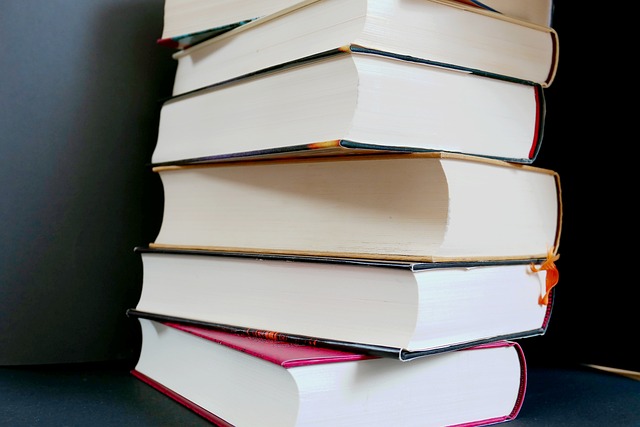 A stack of hardcover books piled on top of each other in front of a dark gray background.