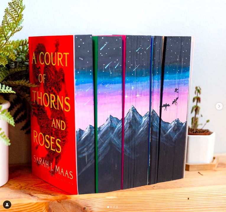 The A Court of Thorns and Roses series by Sarah J. Maas in paperback with their edges painted to show a mountain scene.