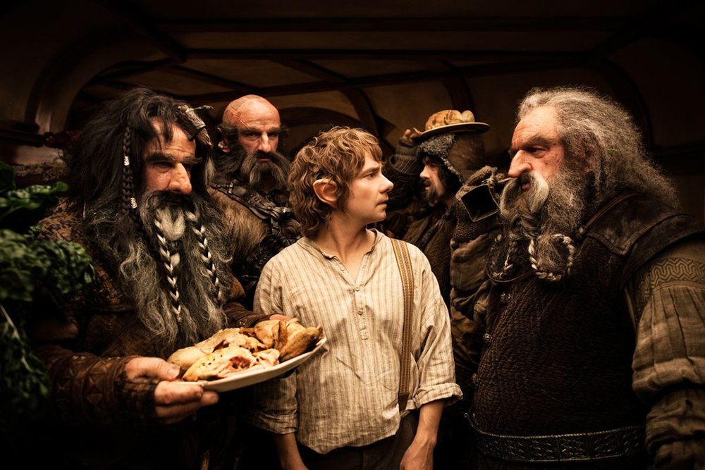 Bifur, Óin, Dwalin, and Bofur surrounding Bilbo in his house