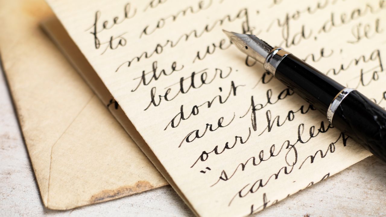 A quill on top of a letter with words written on the paper.