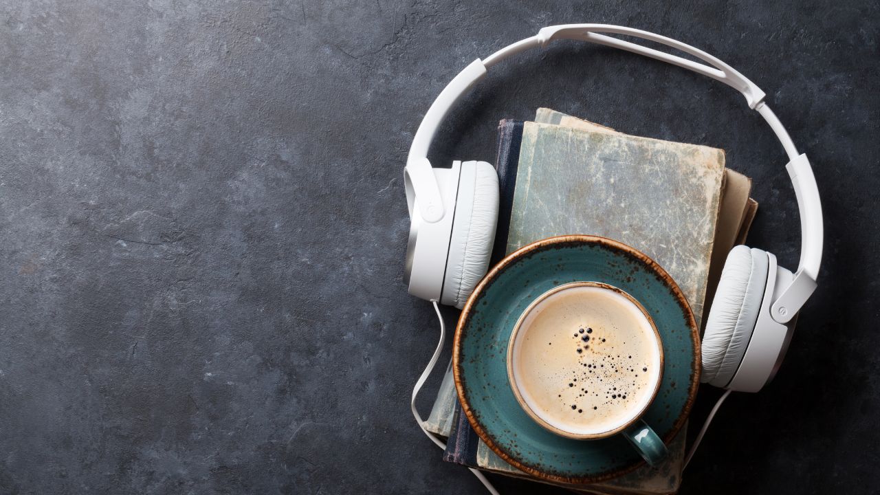 Image showing a cup of coffee on top of some books with headphones around the book.