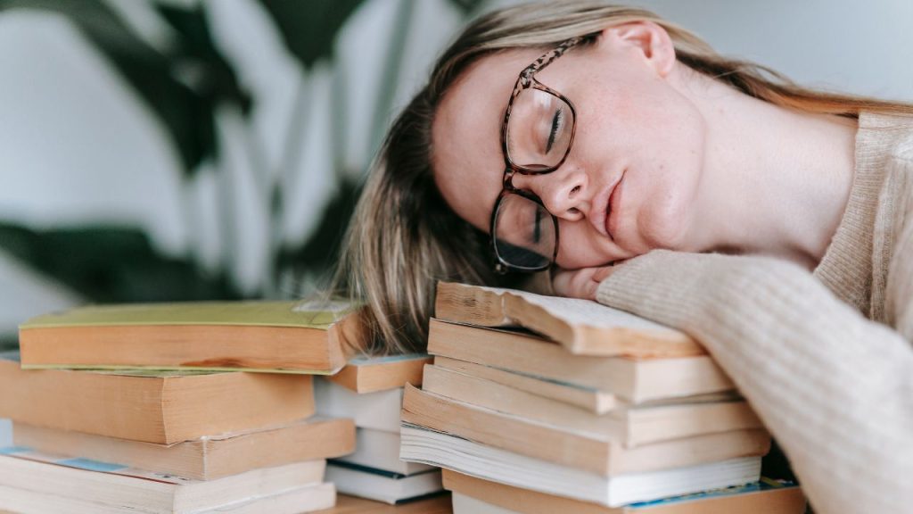 woman sleeping on a pile of books 